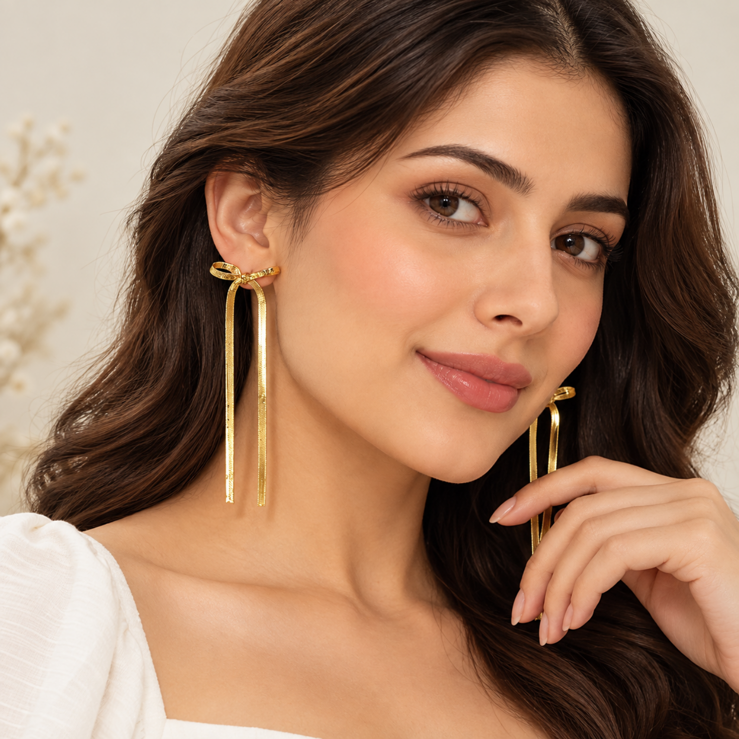Model wearing long gold ribbon bow dangle earrings framing the jawline and neck Model wearing long gold ribbon bow dangle earrings framing the jawline and neck