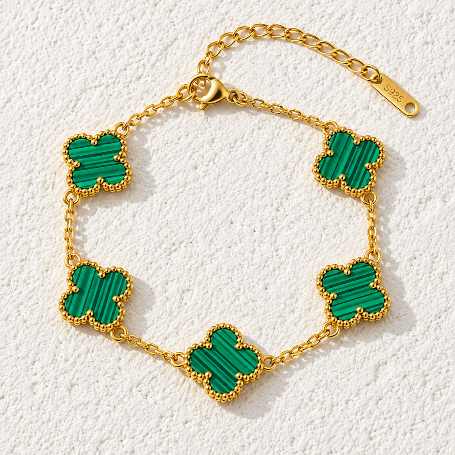 Close-up of striated malachite green clover station bracelet motif framed in golden milgrain beads Close-up of striated malachite green clover station bracelet motif framed in golden milgrain beads