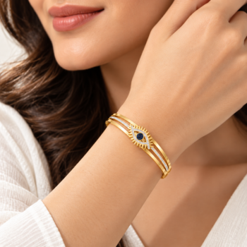 Model wearing Yougorgeous evil eye sunburst hinged bangle stacked with gold chain bracelets
